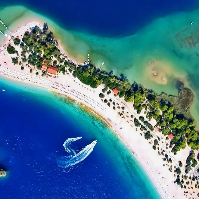 The Ölüdeniz lagoon from above: turquoise water, a sand spit and the wake of one boat