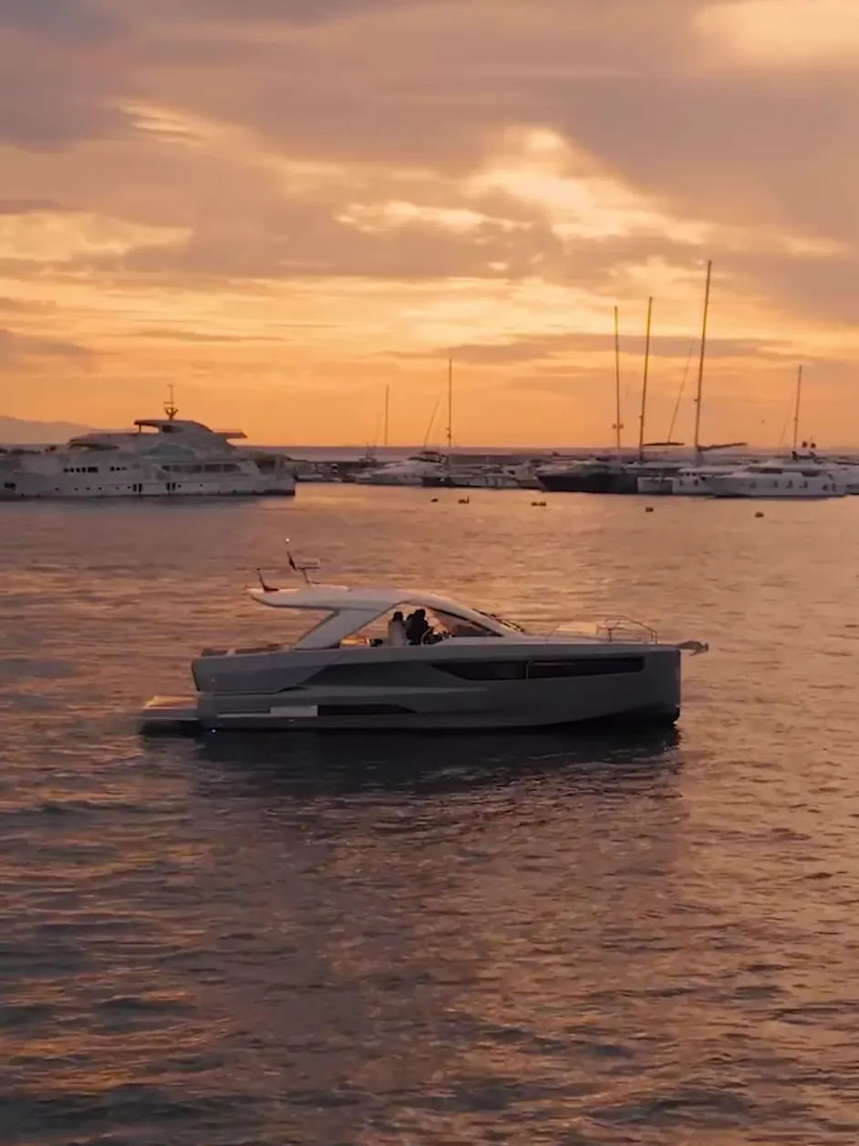 A motor yacht lying off Bodrum at the end of the day, the masts of the marina behind it