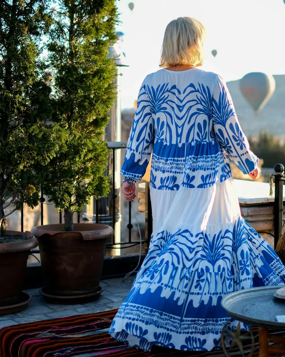 A woman in a blue and white dress crossing a terrace in Cappadocia at first light